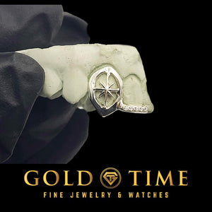 Silver double cap grillz on a mold held in a black glove: an open face canine fang with a 3D starburst inside and a moissanite lined incisor tip