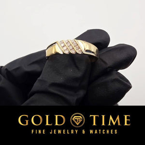 Yellow gold three row diamond band held in a black gloved hand