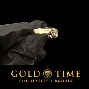 Side view of the yellow gold three row diamond band held in a black gloved hand