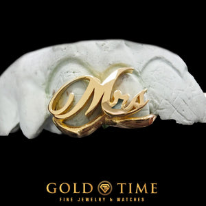 Close-up of yellow gold cursive Mrs. script grill on a dental mold