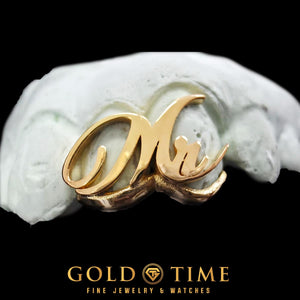 Close-up of yellow gold cursive Mr. script grill on a dental mold