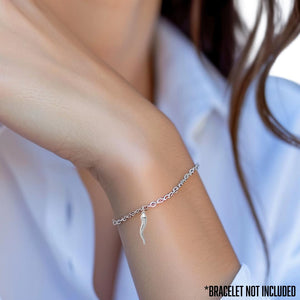 Wrist wearing a small Italian horn charm on a bracelet; bracelet not included
