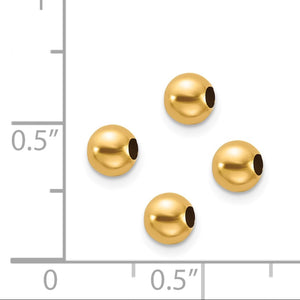 Four 14K gold spacer beads next to a ruler for size