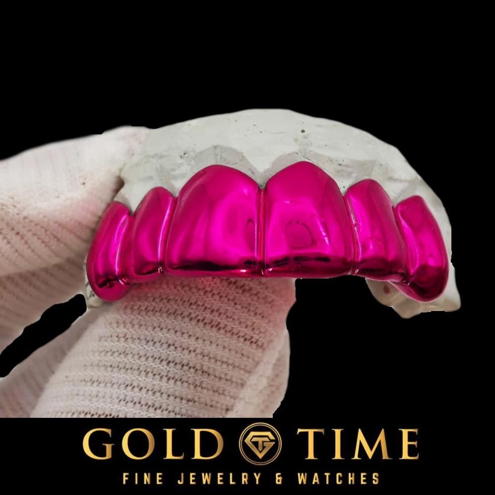 Neon Rose pink chrome solid grillz on a dental mold held in a white gloved hand