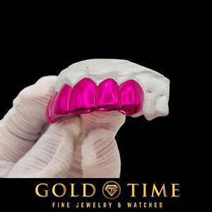 Angled view of Neon Rose pink chrome solid grillz on a mold held in a white glove