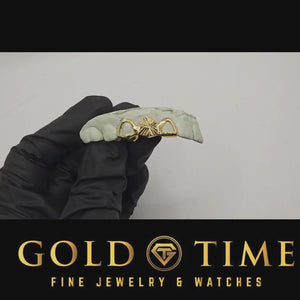 Video of a gloved hand turning a dental mold with the yellow gold 3 piece starburst and open face grill