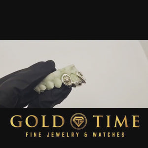 Video of silver starburst open face fang grillz with a moissanite tip, turned on a dental mold in a gloved hand