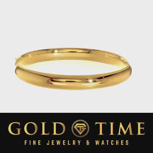 Video of the 14K gold oval hinged bangle turning against a light background