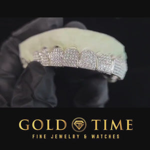 Gloved hand holding an iced out CZ block top grillz set to show the hand set stones