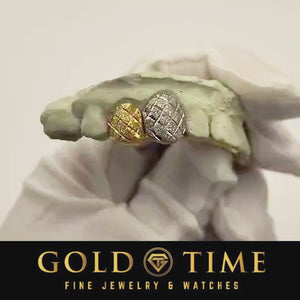 Video of yellow and white two-tone diamond cut double cap grillz turned on a mold in a white gloved hand