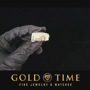 Video of a gloved hand turning a mold with a gold open face canine double cap grill